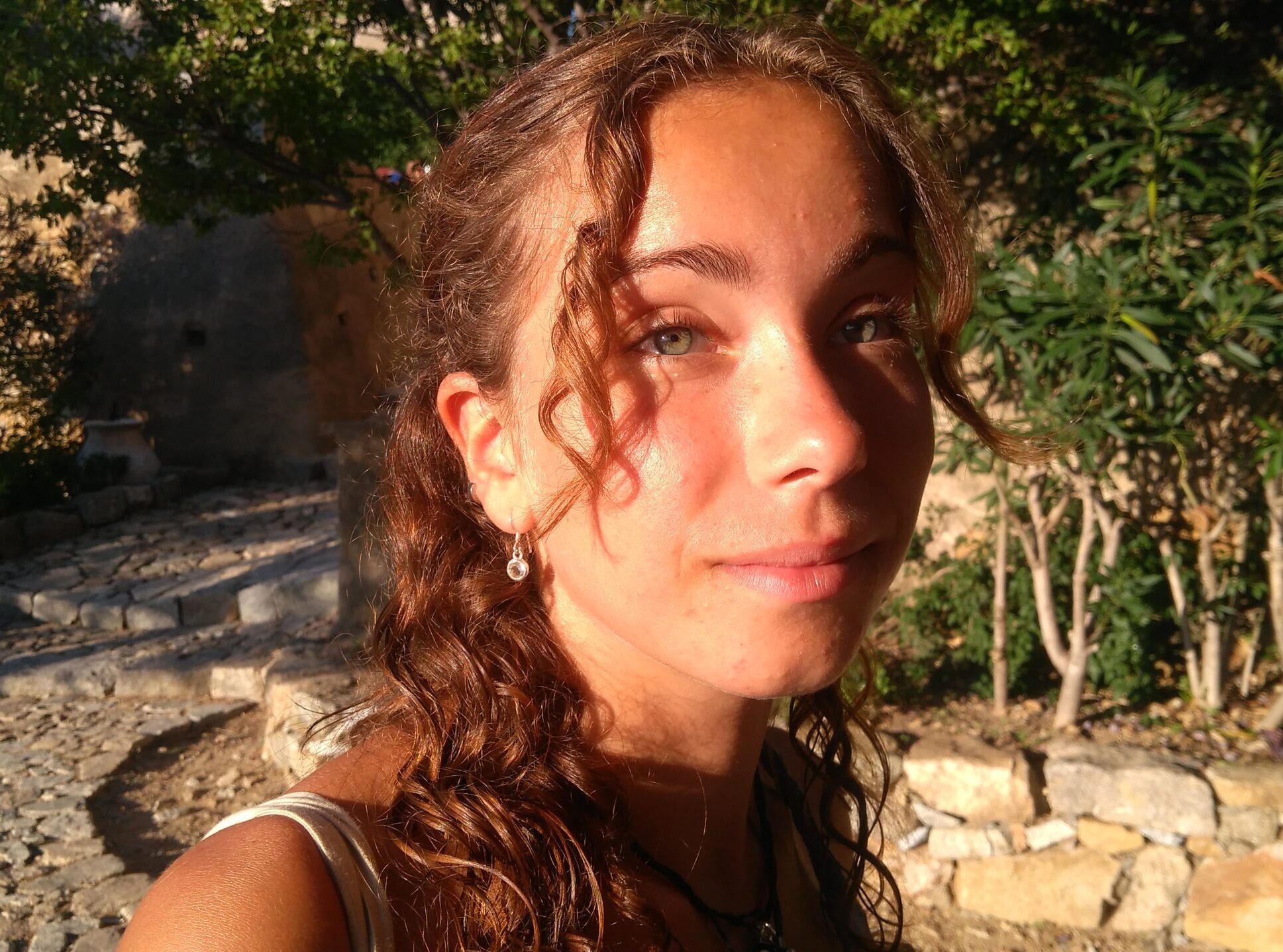 Questa foto di Lola è stata scattata all'aperto in una giornata soleggiata. Ha i capelli lunghi e gli occhi chiari, guarda in camera