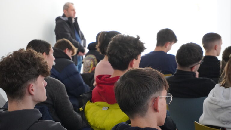 gruppo di studenti ascolta l'intervento di Bergamo Informagiovani. Le persone son ritratte di spalle in una sala.