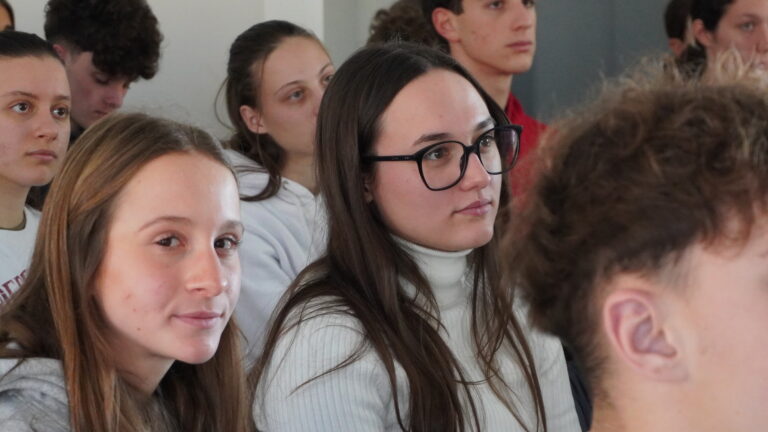 Primo piano di due giovani durante la giornata del placement. Hanno i capelli lunghi e felpe chiare, la persona a sinistra porta gli occhiali.