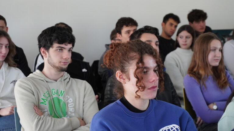 Gruppo di studenti ascolta l'intervento di Bergamo Informagiovani durante le giornata del placement. In primo piano una persona seduta, con capelli legati, ricci e felpa blu