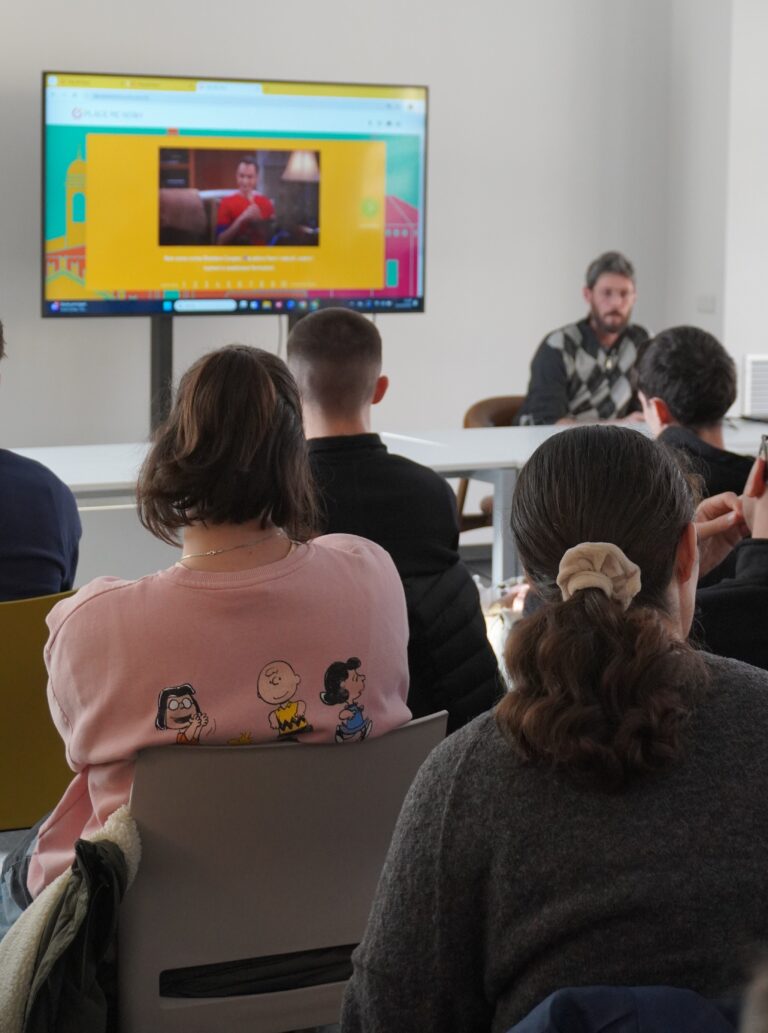 Un consulente di orientamento al lavoro parla con un gruppo di studenti, mostrando un sito.