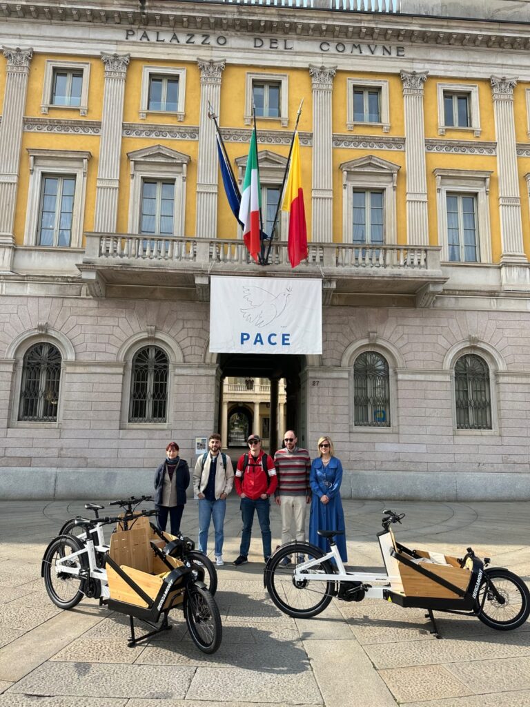 Due educatori di Giovani Onde, due persone dello staff comunale e l'assessora Marcella Messina posano insieme a tre bike e-cargo, davanti a Palazzo Frizzoni, sede del Comune di Bergamo, in piazza Matteotti.