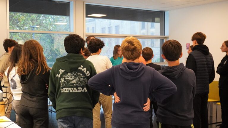 un gruppo di studenti di terza durante un incontro diorientamento. IL gruppo è ripreso di spalle in una stanza con grandi finestre.