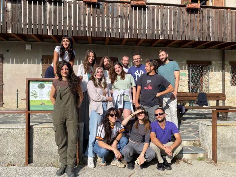 Un gruppo di ragazze e ragazzi posa di fronte a un rifugio di montagna. Sono le artiste e gli artisti dell'edizione 2023 di Sentieri Creativi, insieme al professor Francesco Pedrini.