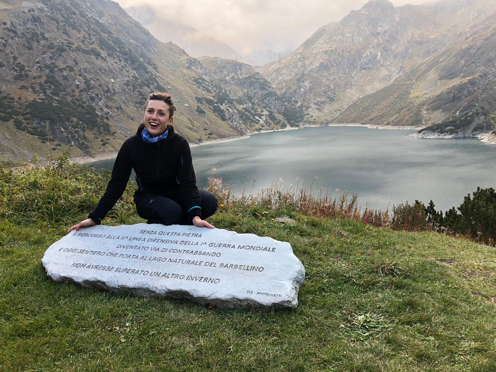 L'artista posa con la sua opera, una lastra di pietra liscia posta di fronte a un lago, con inciso sopra questa frase: 