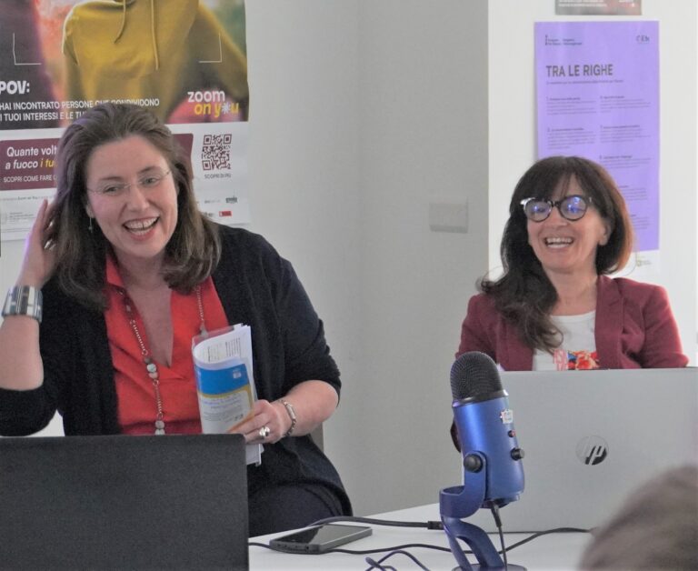Immagine che ritrae due persone, le formatrici dell'incontro, che sorridono serenamente. Davanti a loro due pc e un microfono