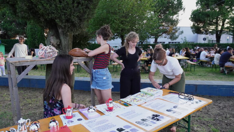 Gruppo di giovani intorno a un tavolo all'aperto. Sul tavolo diversi volantini