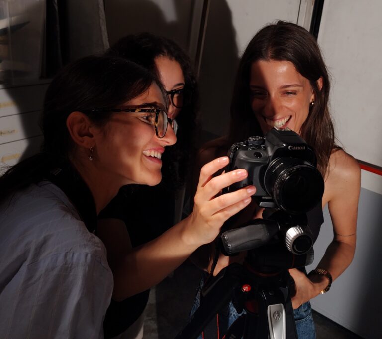 tra persone sorridono intorno a una macchina fotografica
