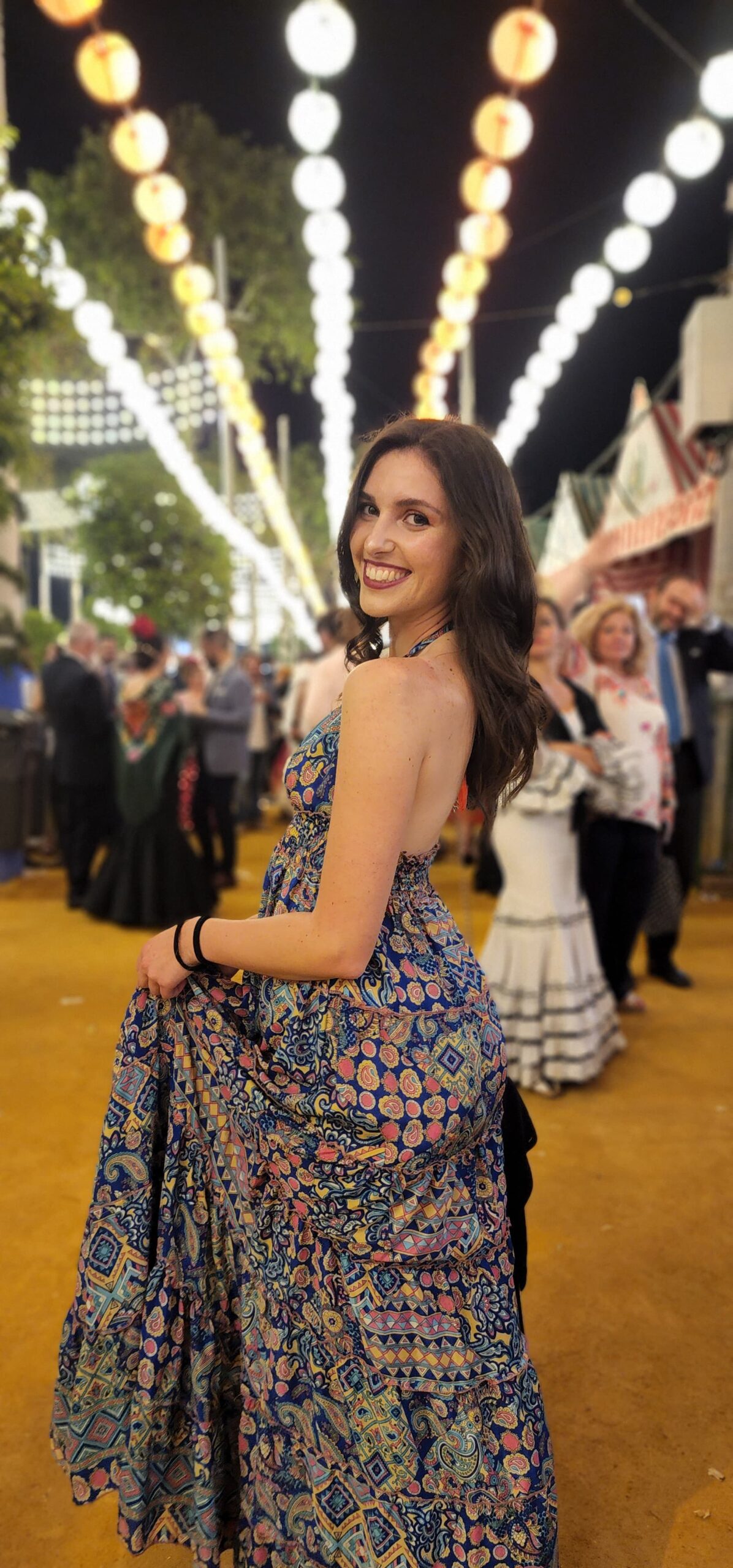 Beatrice ad un evento, sorride e indossa un vestito con motivi colorati.