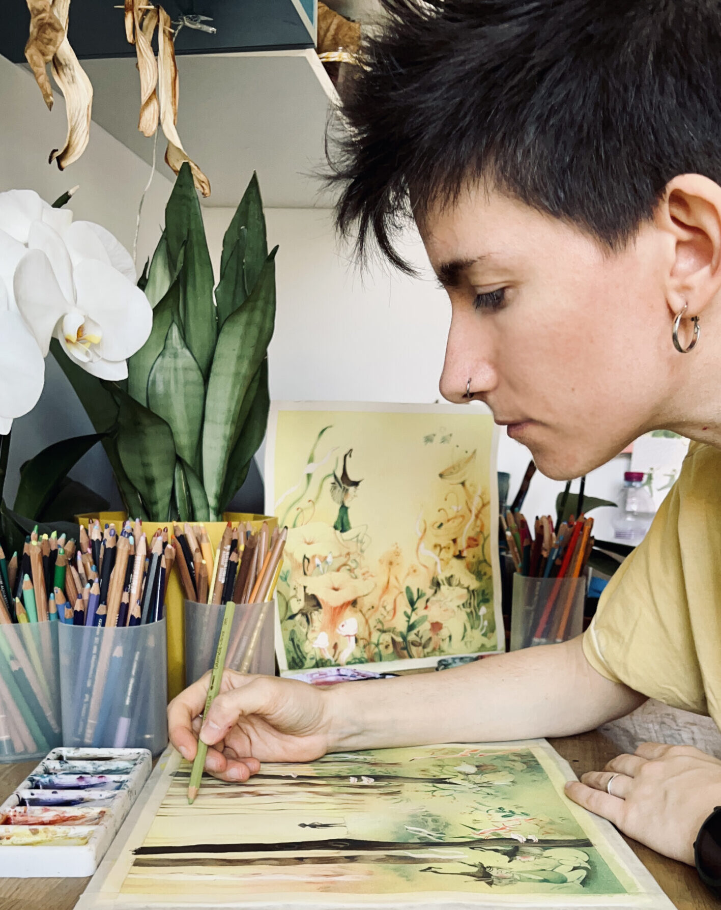 Elena dipinge un quadro naturalistico con dei pastelli, seduta alla scrivania.