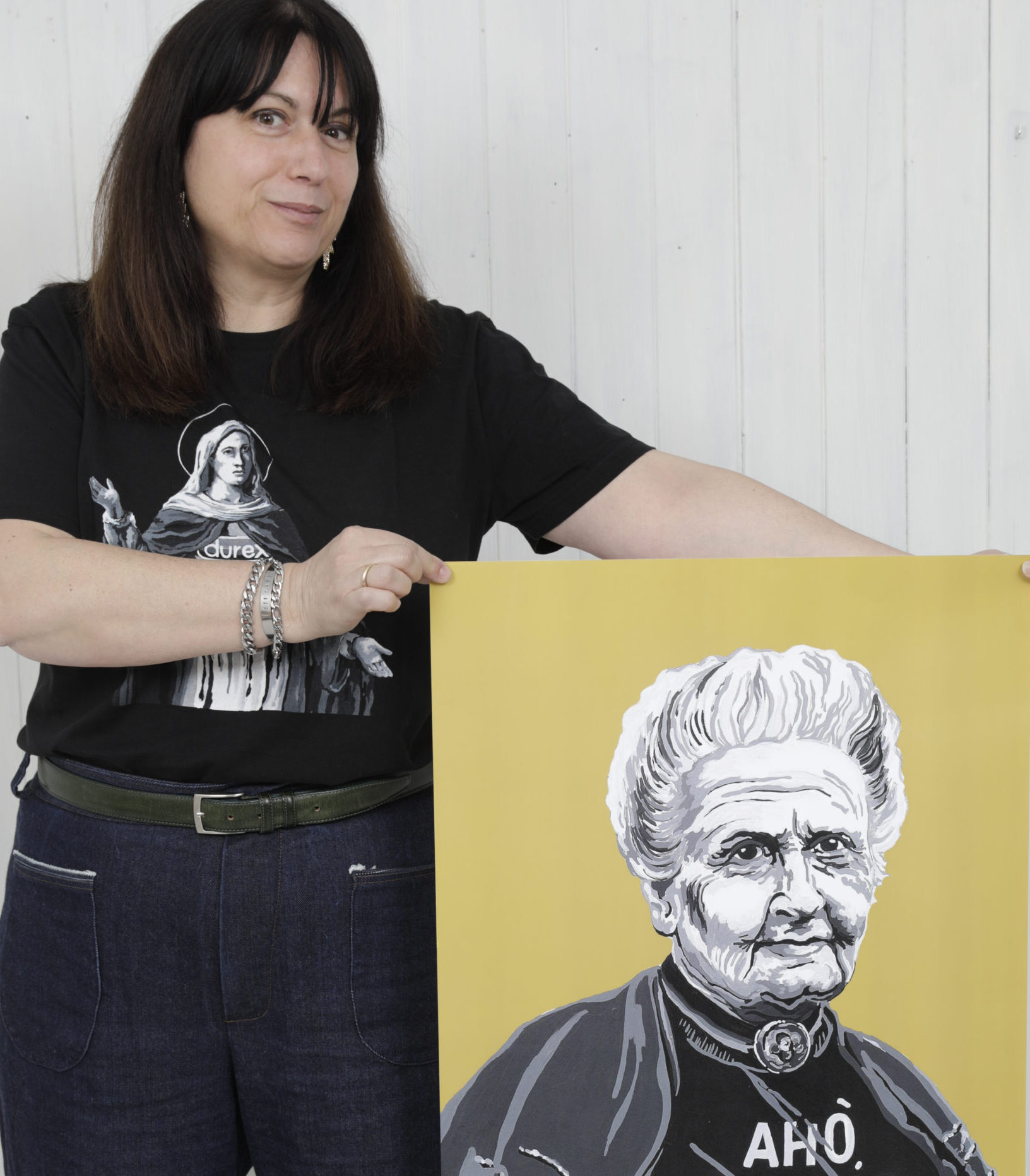 Sara è in piedi e tiene in mano un suo dipinto che ritrae Maria Montessori in bianco e nero, su sfondo giallo. Sul quadro è rafigurata anche la scritta: 