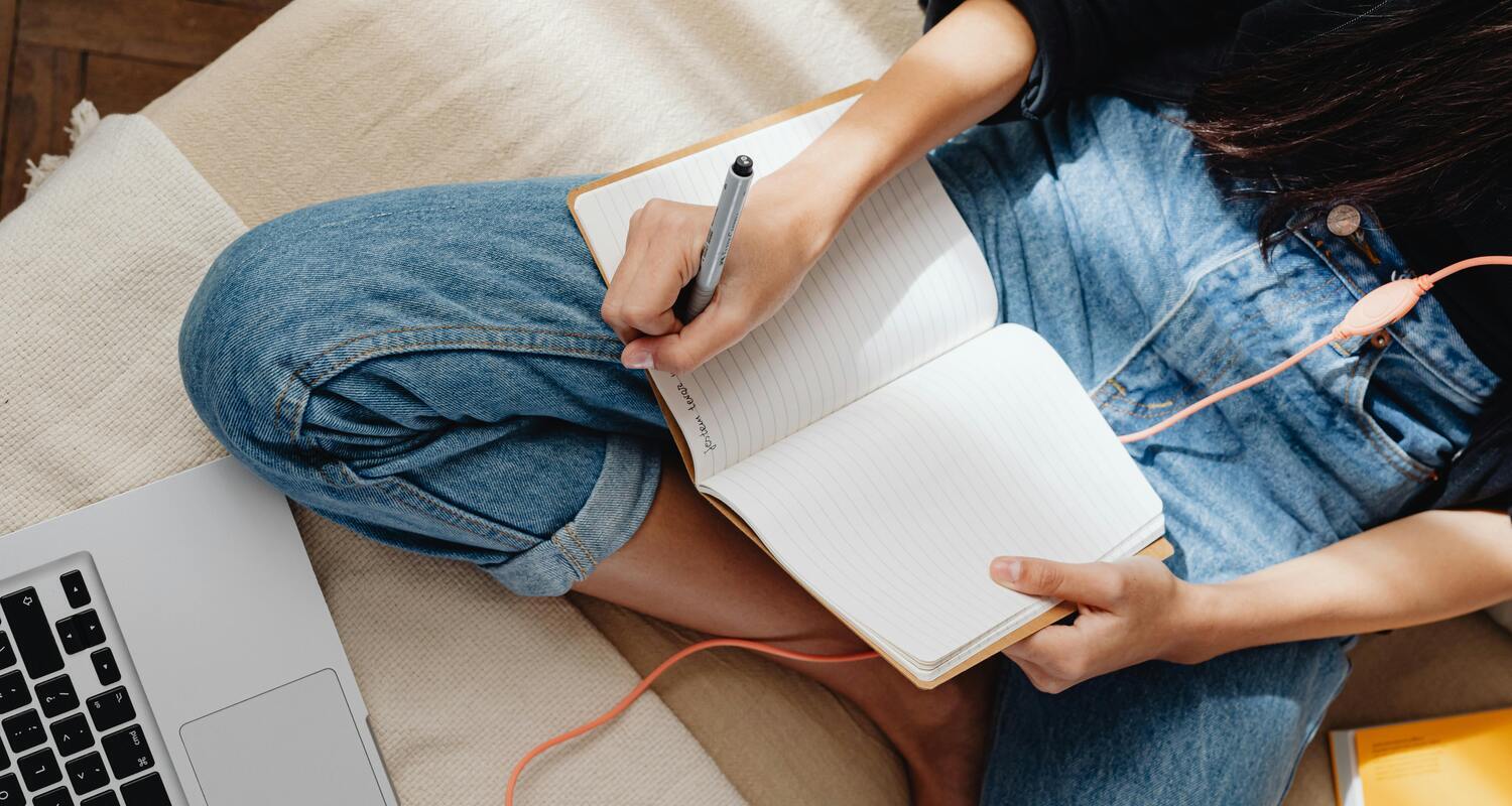 Una ragazza fotografata dall'alto scrive su un quaderno.