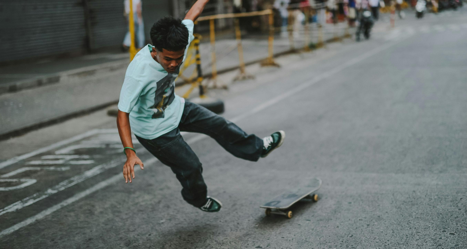 Un ragazzo è fotografato nell'atto di saltare dallo skateboard, sospeso in aria.