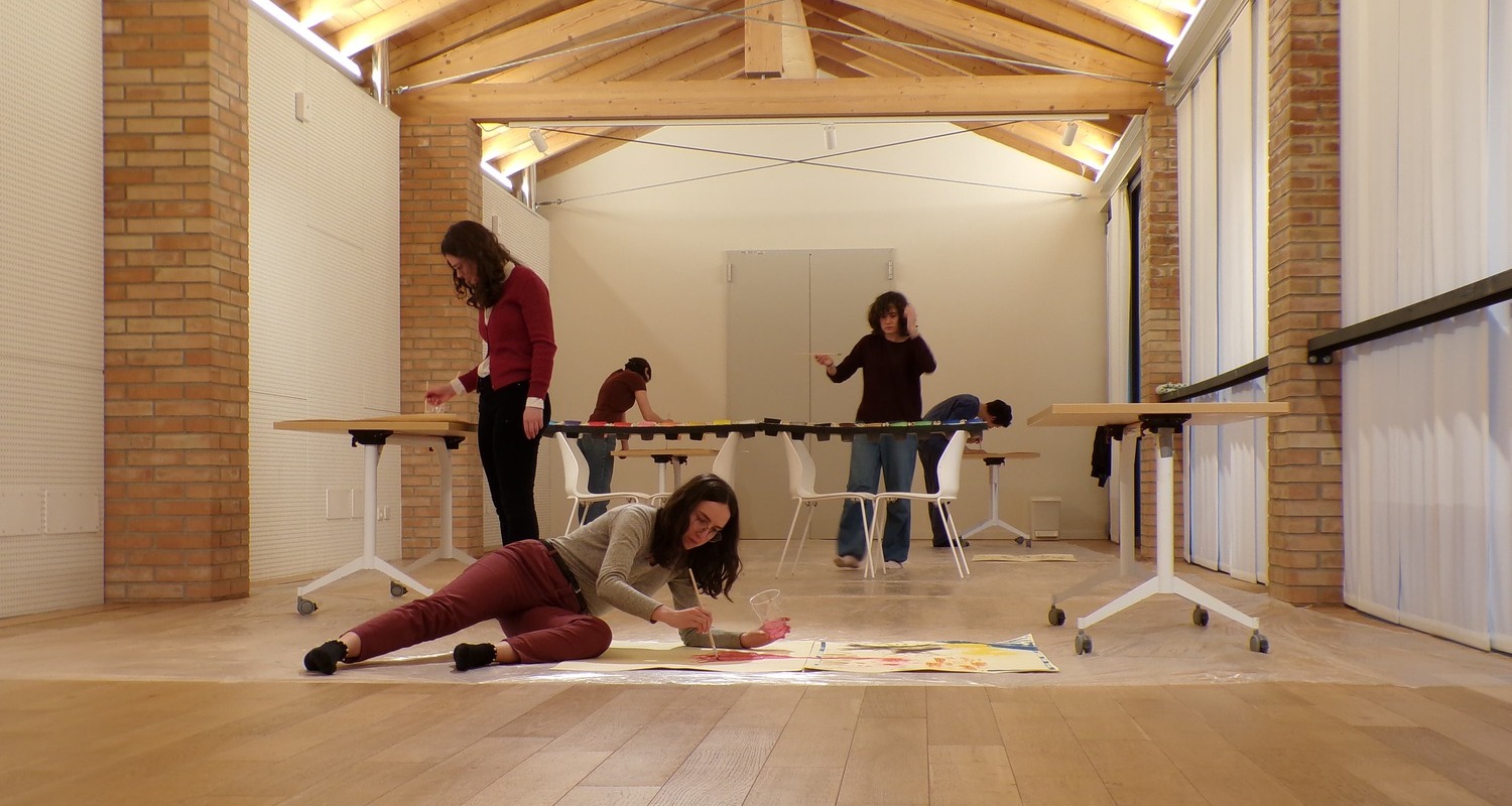 Quattro ragazze e un ragazzo dipingono con pennelli e colori a tempera.