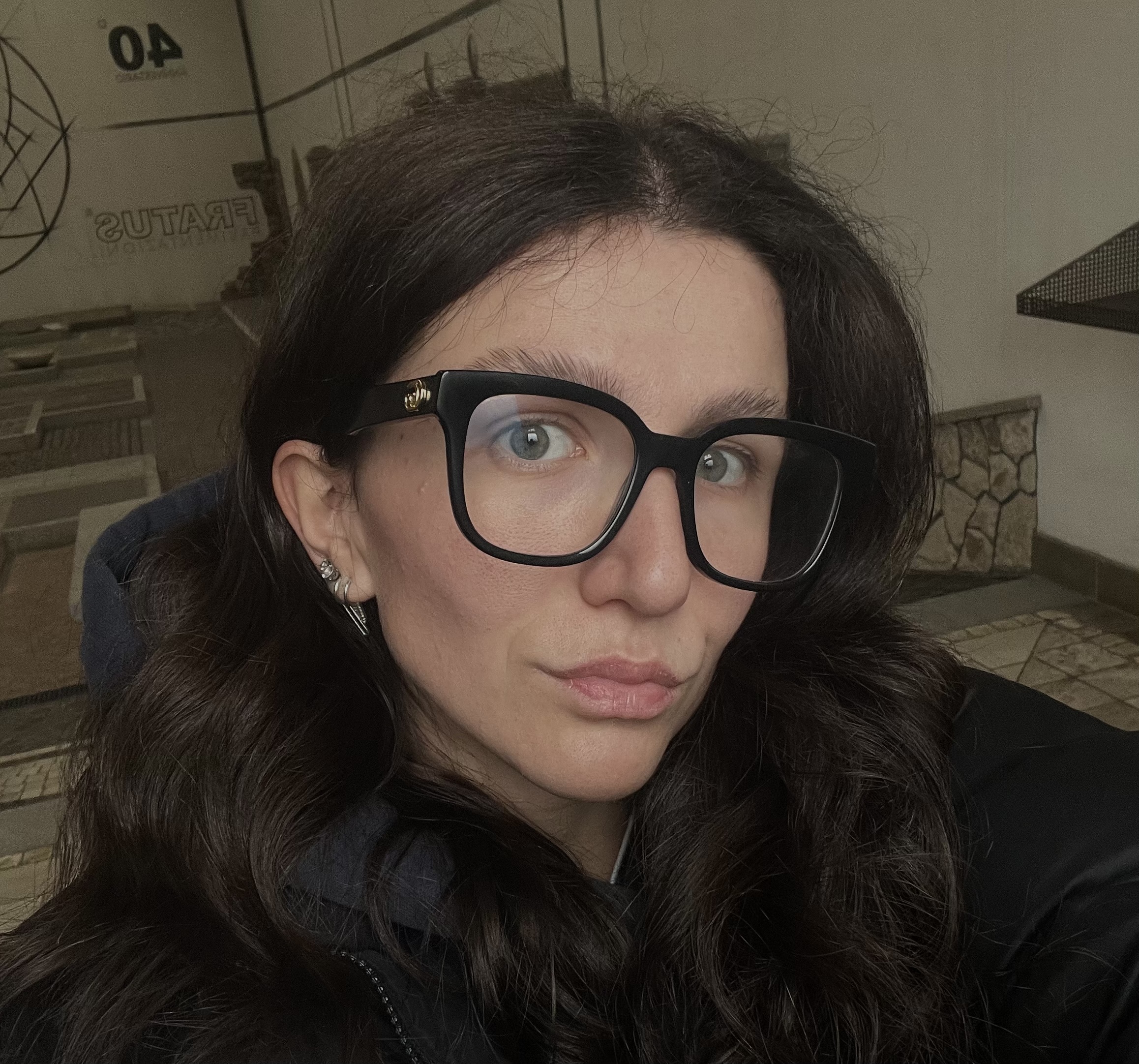 Nella foto c'è il primo piano di Bea. Indossa occhiali da vista grandi e neri, e una felpa nera. Ha i capelli lunghi e castano scuro.