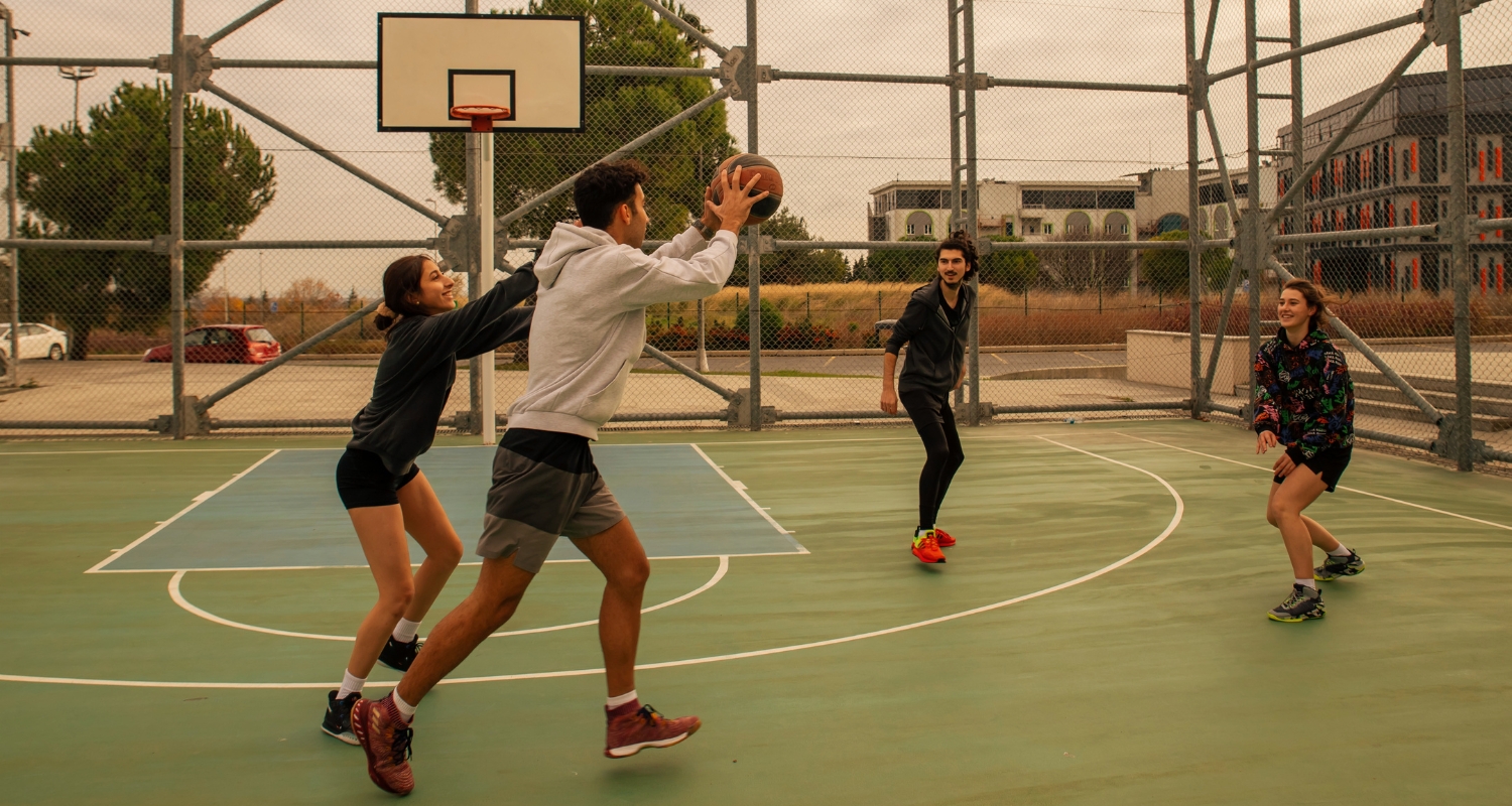 Quattro giovani giocano a basket nel campo all’aperto
