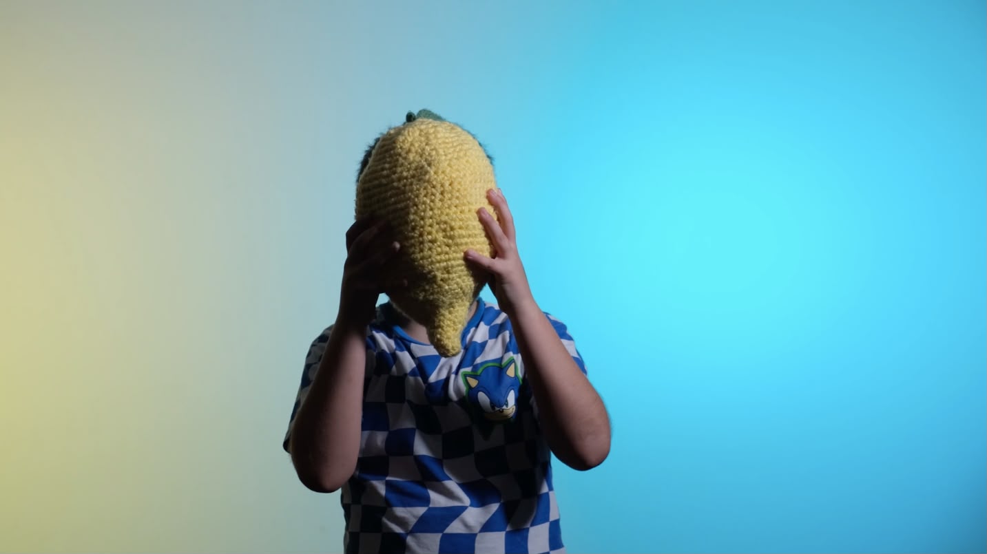Immagine che ritrae una persona in una dimensione artistica: ha un limone gigante davanti alla faccia e le luci sono tra blu e giallo
